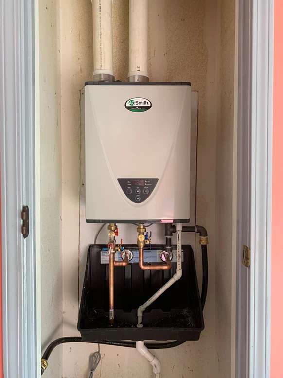 An AO Smith tankless water heater connected to copper and PVC piping.