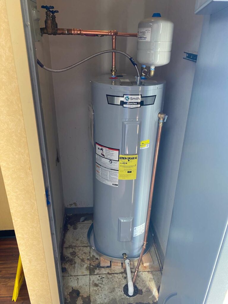 A brand new gray water heater and expansion tank in a closet.