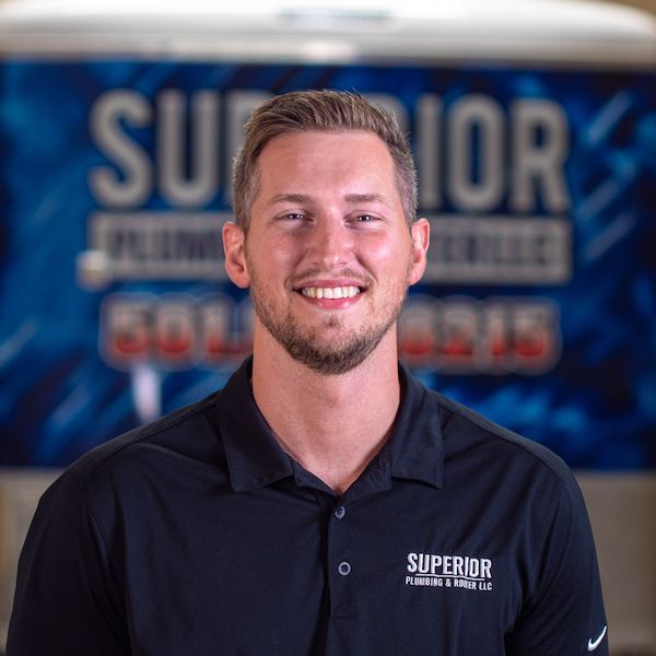 Superior Plumbing & Rooter LLC employee Sean in a black company polo. Sean has a patchy brown beard and short brown hair.